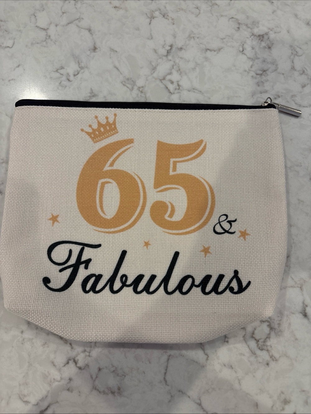 Tan canvas cosmetic makeup bag features gold crown & printed text 65 & Fabulous